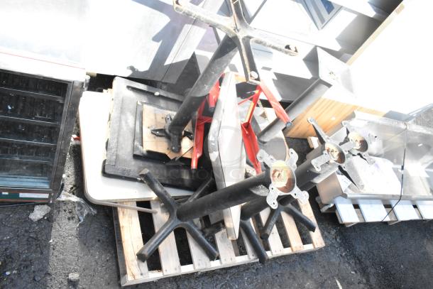 Stack of five disassembled tables with black metal bases and wood tops, placed on a pallet, showing wear.