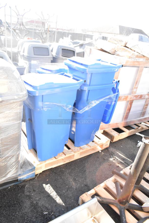 Four blue poly trash cans stacked on a wooden pallet outdoors, in new condition.
