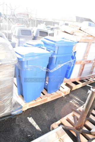 Four blue poly trash cans stacked on a wooden pallet outdoors, in new condition.