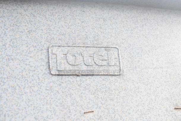 Toter gray poly trash can shell, marked with "Toter" logo. Includes 12 units per bid. Durable construction.