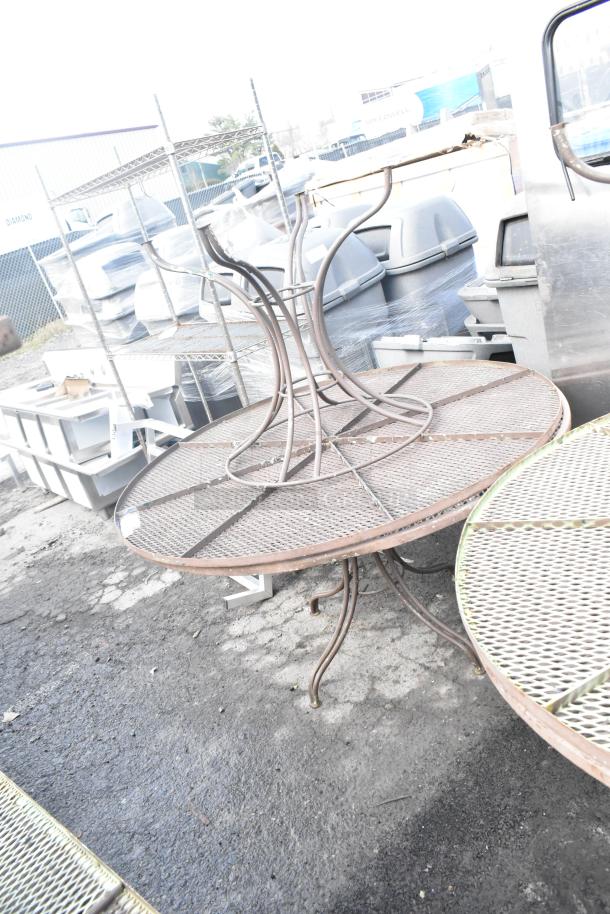 4 round mesh patio tables with bronze finish, metal frames, and lattice tops, showing signs of weathering.