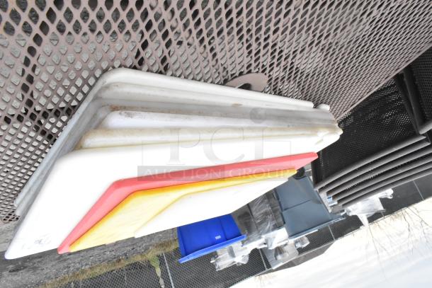 Stack of 10 various cutting boards with white, red, and yellow edges on a metal surface, showing moderate wear.
