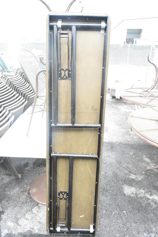 Folding table with metal legs, shown in a closed position, alongside similar outdoor seating items in good condition.