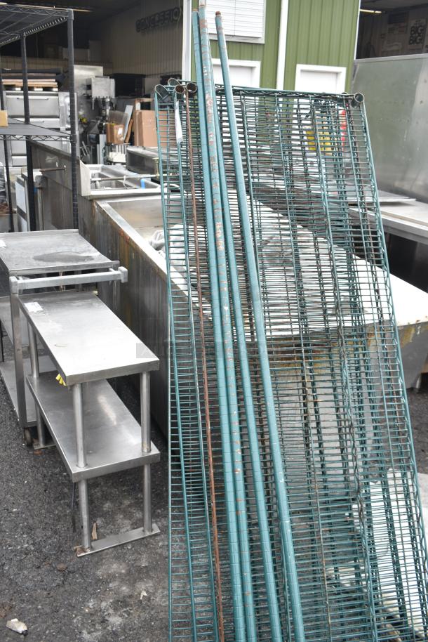 Lot of green wire shelves and poles, showing signs of wear. Ideal for storage use.
