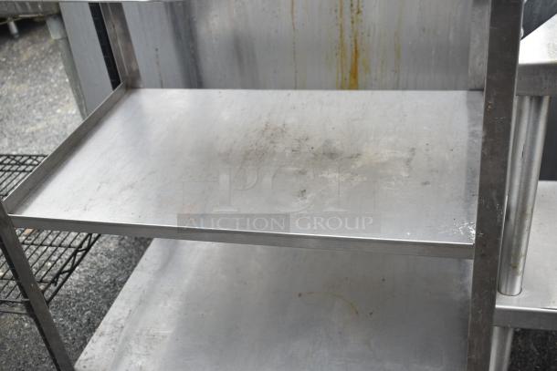Commercial 3-tier stainless steel cart with wheels, featuring sturdy construction; visible wear and surface marks.