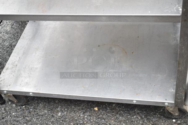 Commercial 3-tier stainless steel cart on heavy-duty casters; used condition with visible wear and surface markings.
