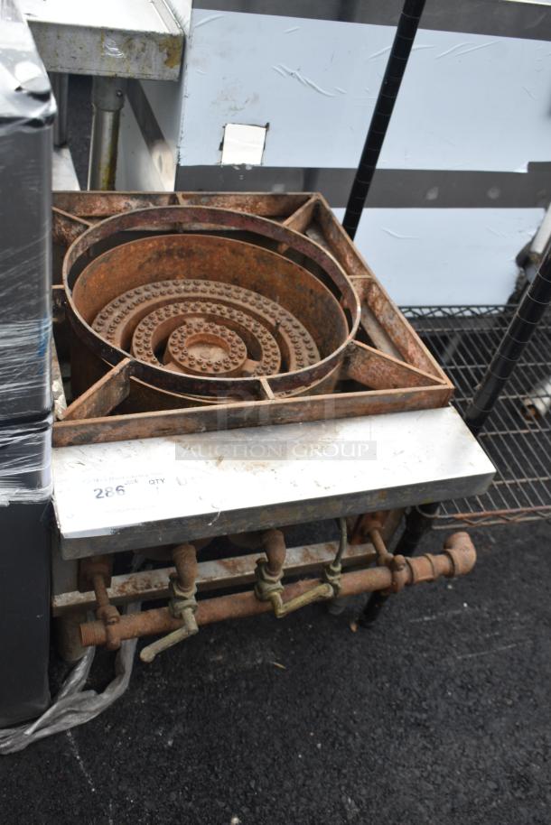 Commercial gas-powered single burner range, rusted condition, with visible gas valves and metal frame.