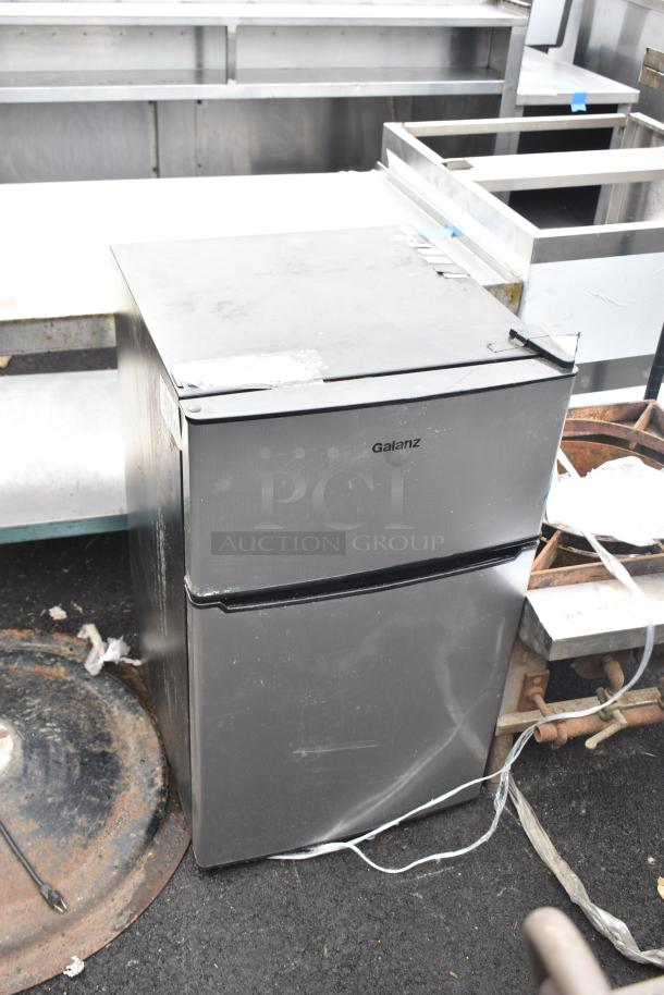 Galanz GLR31TS1E02 mini cooler with freezer, gray finish, visible wear. Model and brand name on front. 115 Volts, 1 Phase.