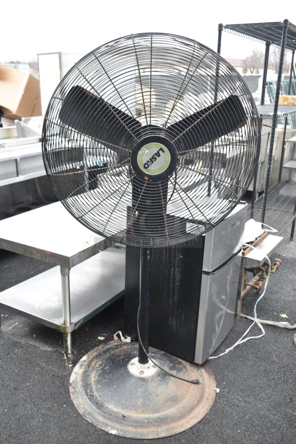 Lasko floor fan with three blades, black stand, and circular base. Label indicates 115 volts, 1 phase. Slightly worn.