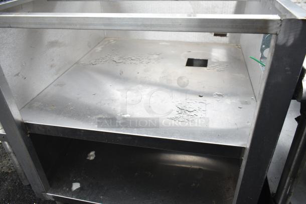 Commercial equipment stand with under shelves, made of stainless steel. Visible wear and surface imperfections.