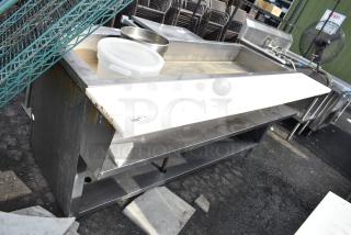 Commercial steam table with stainless steel construction, visible signs of wear, includes storage shelf; item tag 293.