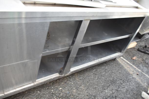 Commercial prep station with under shelves, stainless steel, showing wear. Ideal for kitchen use, sturdy construction.