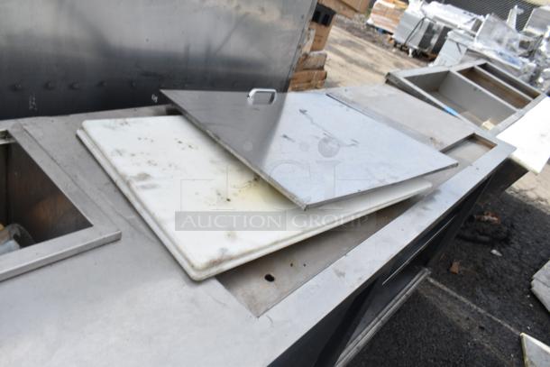 Commercial prep station with under shelves, stainless steel, used condition, visible cutting board, and metal lid.