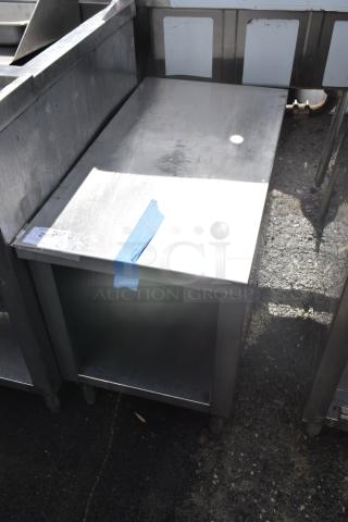 Stainless steel commercial equipment stand with under shelf, showing minor surface wear, blue tape marker on top corner.
