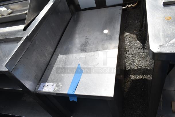 Commercial equipment stand with under shelf, stainless steel, used condition. Blue tape and a label with code are visible.