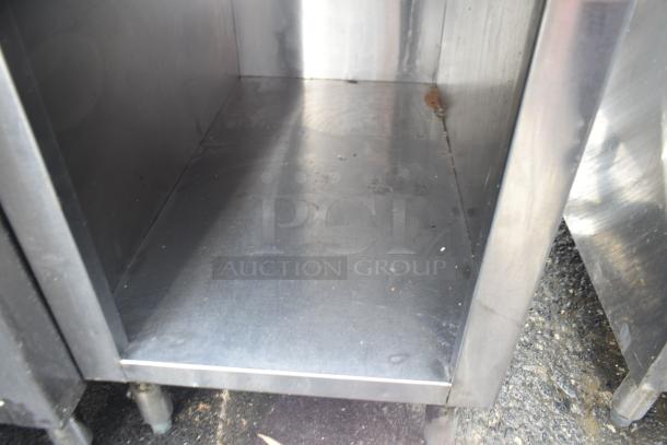 Stainless steel commercial equipment stand with under shelf, showing minimal wear and sturdy construction.