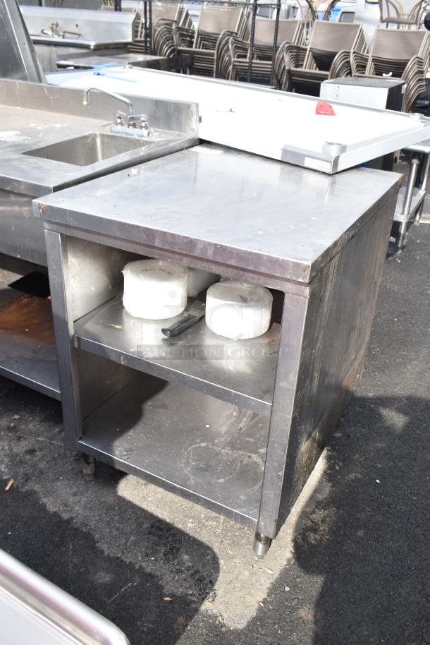 Stainless steel commercial table with two under shelves, showing signs of wear, ideal for kitchen use.