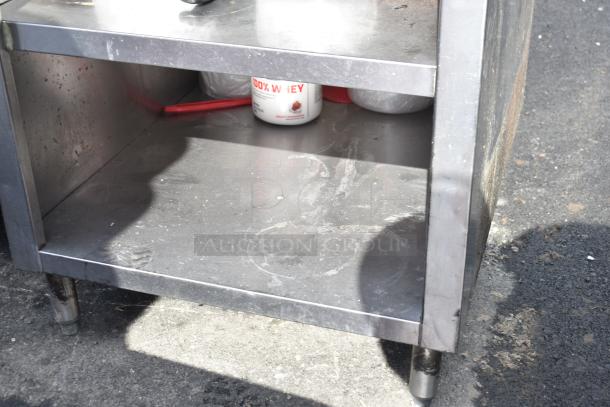Commercial stainless steel table with under shelves, sturdy design, slight wear visible, ideal for industrial use.