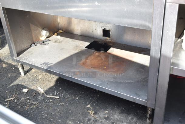 Commercial table with sink bay and under shelf, stainless steel, showing signs of rust and wear, suitable for kitchen use.
