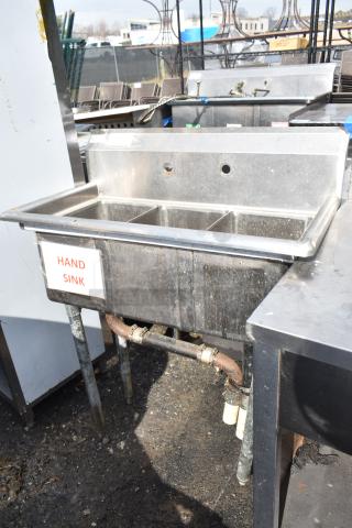Commercial 3 bay stainless steel sink, labeled "Hand Sink," with visible plumbing; outdoor setting, used condition.