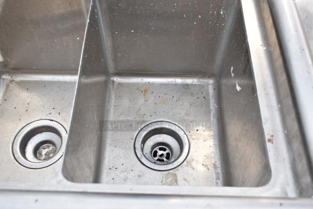 Commercial 3 bay stainless steel sink in used condition, visible dirt and wear, featuring three separate basins and drains.