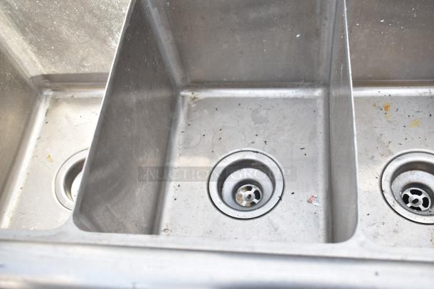 Commercial 3 bay sink, stainless steel, used condition with visible signs of wear, three drains, no visible markings.