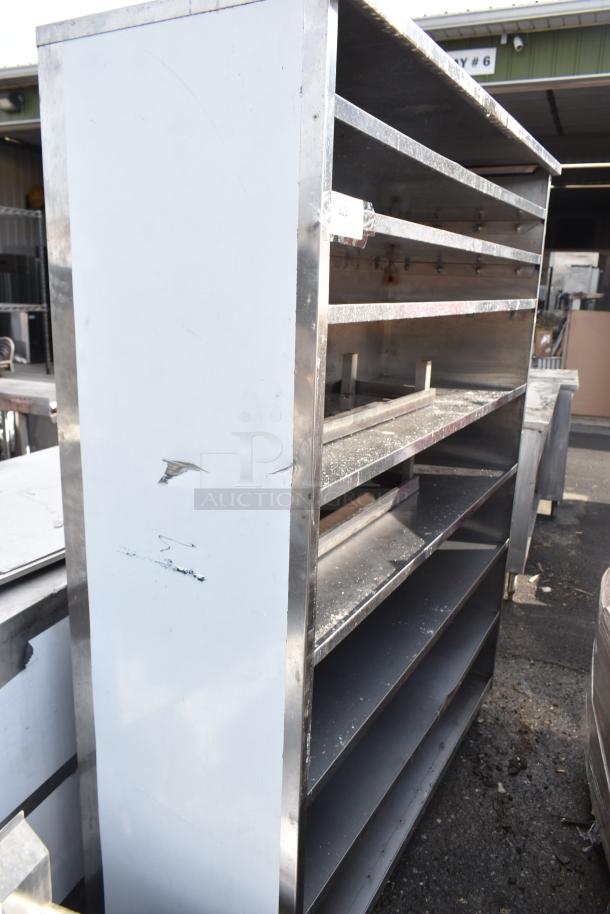 Commercial shelving unit, metal frame with five shelves, moderate wear, scuffs on the side; suitable for industrial use.