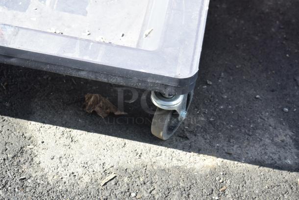 Dolly with handle on commercial casters, sturdy frame, some wear visible, ideal for industrial use.