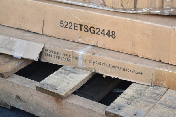 Boxes labeled "522ETSG2448" and "600UTPB3048S" on a pallet, containing scratch and dent kitchen tables.