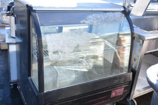 Turbo Air commercial deli display case with glass front, visible frost, and interior shelving; shows wear and outdoor exposure.