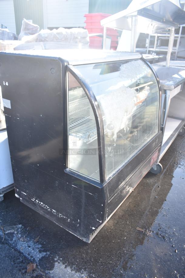 Turbo Air commercial floor-style deli display case with glass front, showing signs of wear, suitable for storing and showcasing deli items.