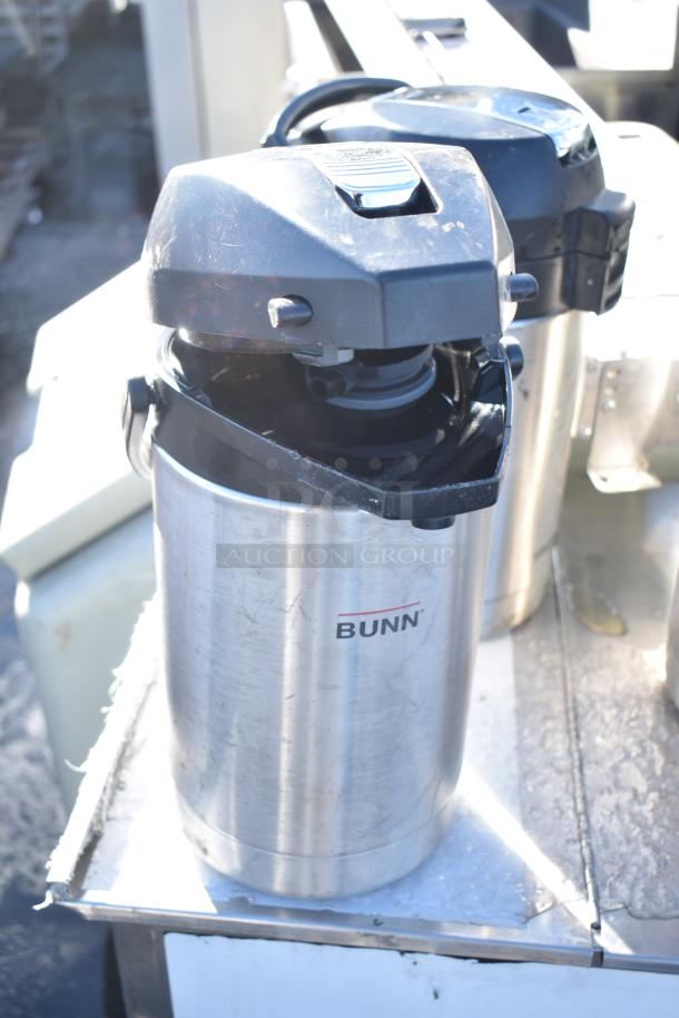 Three stainless steel Bunn countertop air pots, featuring black lids and dispensing mechanisms, in used condition.