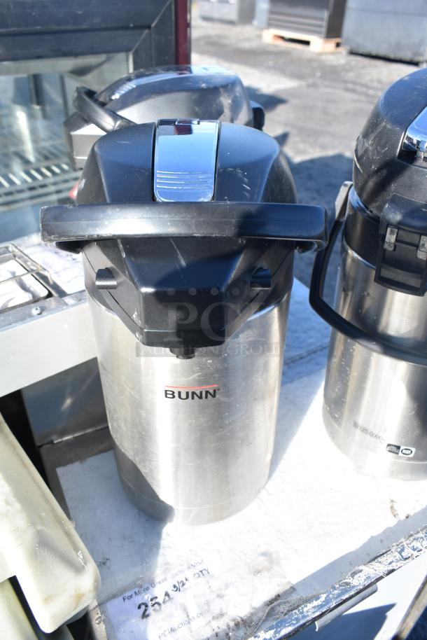 Three Bunn countertop air pots, stainless steel, black lids, used condition, visible labels, ideal for beverage service.