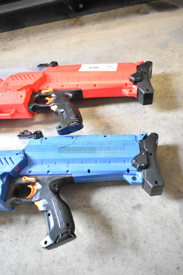 Two Nerf Rival toy guns, red and blue, in good condition. Black grips and orange accents on each. Label visible on red gun.