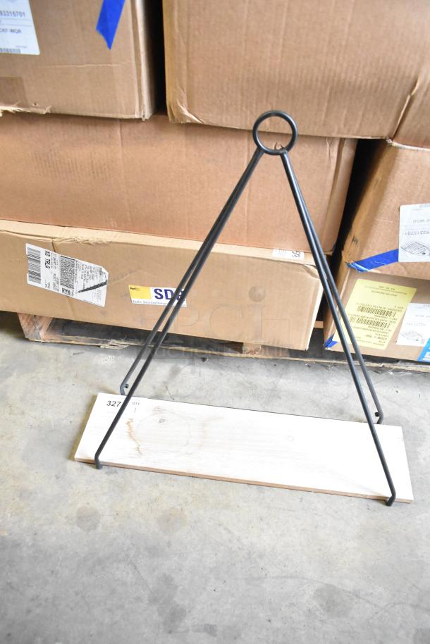 Black metal triangular stand with wooden base, new condition. Barcode and shipment labels visible on surrounding boxes.