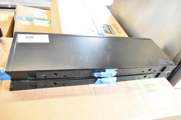 Pair of black metal shelves, light signs of wear, stacked on cardboard. Label on top shelf indicates "328, QTY x2."