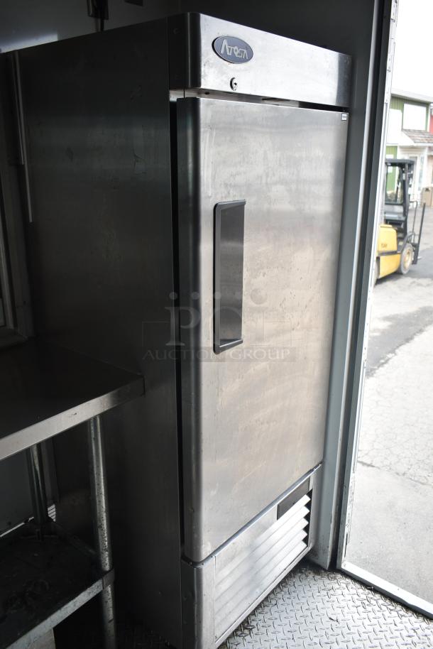 Stainless steel fridge inside 2002 Freightliner food truck with propane hookup, grease hood, fryer, griddle, and serving window.