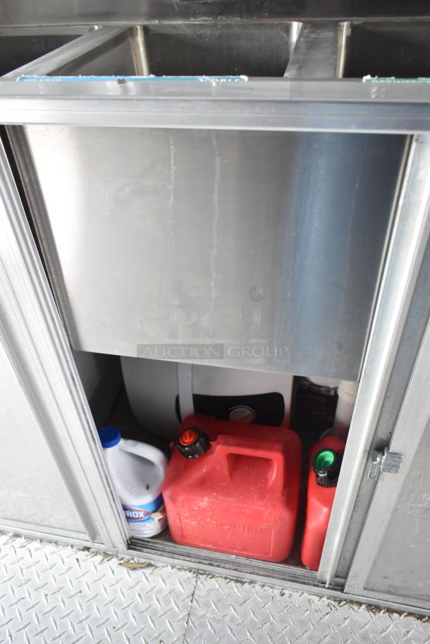 Interior storage compartment of a 2002 Freightliner Food Truck, showing red fuel canisters and a Clorox container.