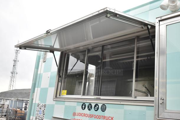 2002 Freightliner Ludicrous food truck with serving window, propane hookup, grease hood, fryer, griddle, grill, and refrigeration.