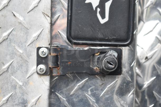 Lock mechanism on a diamond plate surface of a 2002 Freightliner Ludicrous Food Truck, showing signs of rust.