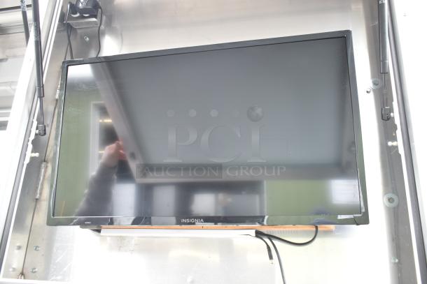 A flat-screen Insignia TV mounted inside a 2002 Freightliner food truck, reflecting part of the truck’s interior.