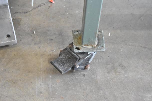 Commercial caster of Lenin gas-powered chip fryer, slightly worn, showing sturdy metal frame and locking mechanism.