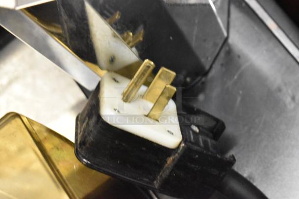 Thermoplan Mastrena II Espresso Machine plug, showing dual brass prongs and black casing on stainless steel countertop.