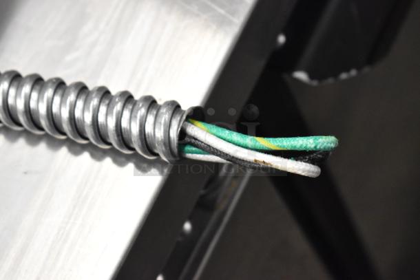 Coiled electrical cable with exposed wires next to a metal surface, likely part of Hatco HWB-11QTD setup.