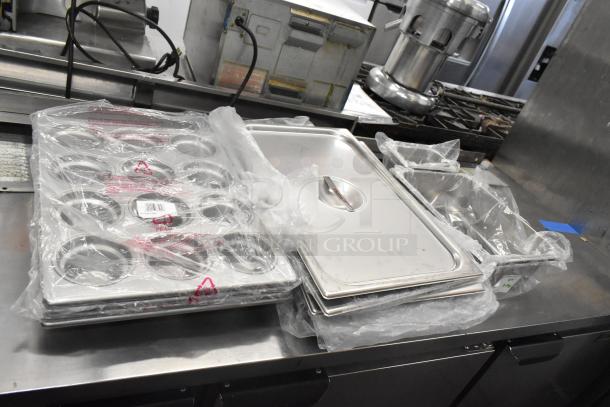 Brand new kitchen items including muffin pans, lids, and bins. Scratch and dent condition, wrapped in plastic packaging.