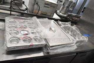 Brand new kitchen items including muffin pans, lids, and bins. Scratch and dent condition, wrapped in plastic packaging.