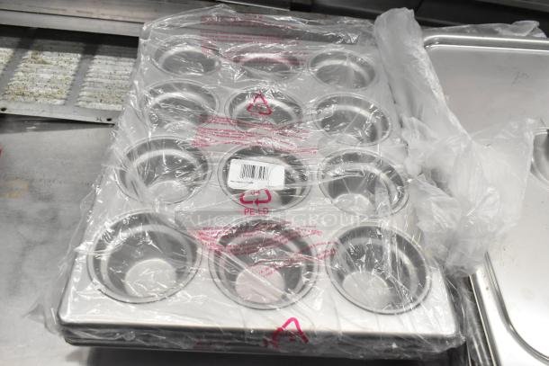 Brand new muffin baking pans, wrapped in plastic, showing scratch and dent condition. Includes barcode label.