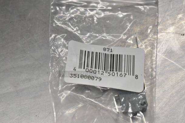 Clear plastic bag with barcode label showing number 871 and code 351080079, contains small metal component.