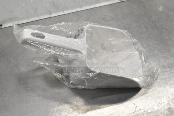 Plastic dustpan in original packaging on metal surface, unused. Part of a lot including mixing bowl, door switch, and tablets.