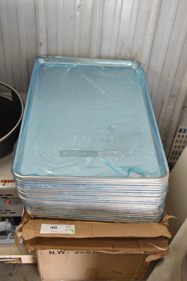 29 brand new scratch and dent aluminum bun pans, size 18" x 26", 19 gauge, stacked with protective blue wrap.